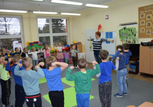 Dzieci stoją z nauczycielką w kole, wykonują ćwiczenia rąk